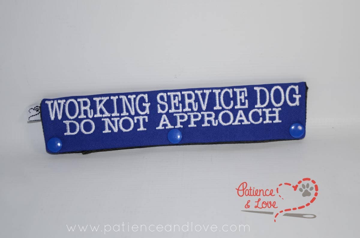 Blue sleeve with white text that says WORKING SERVICE DOG DO NOT APPROACH