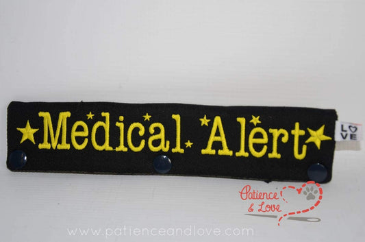 Black leash sleeve with yellow text.  It reads Medical Alert and has small stars around the text.