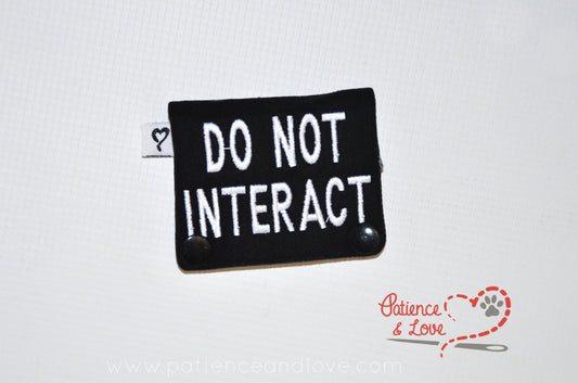 One Leash Sleeve embroidered with the following on both sides of the sleeve:       DO NOT INTERACT     Example in the listing photo has the following color selections:        • Black fabric, white text