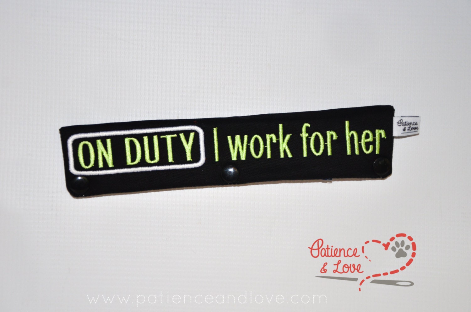 Black Leash sleeve with text that says ON DUTY I work for her.  the text is in an apple green and the on duty text is circled in white thread.